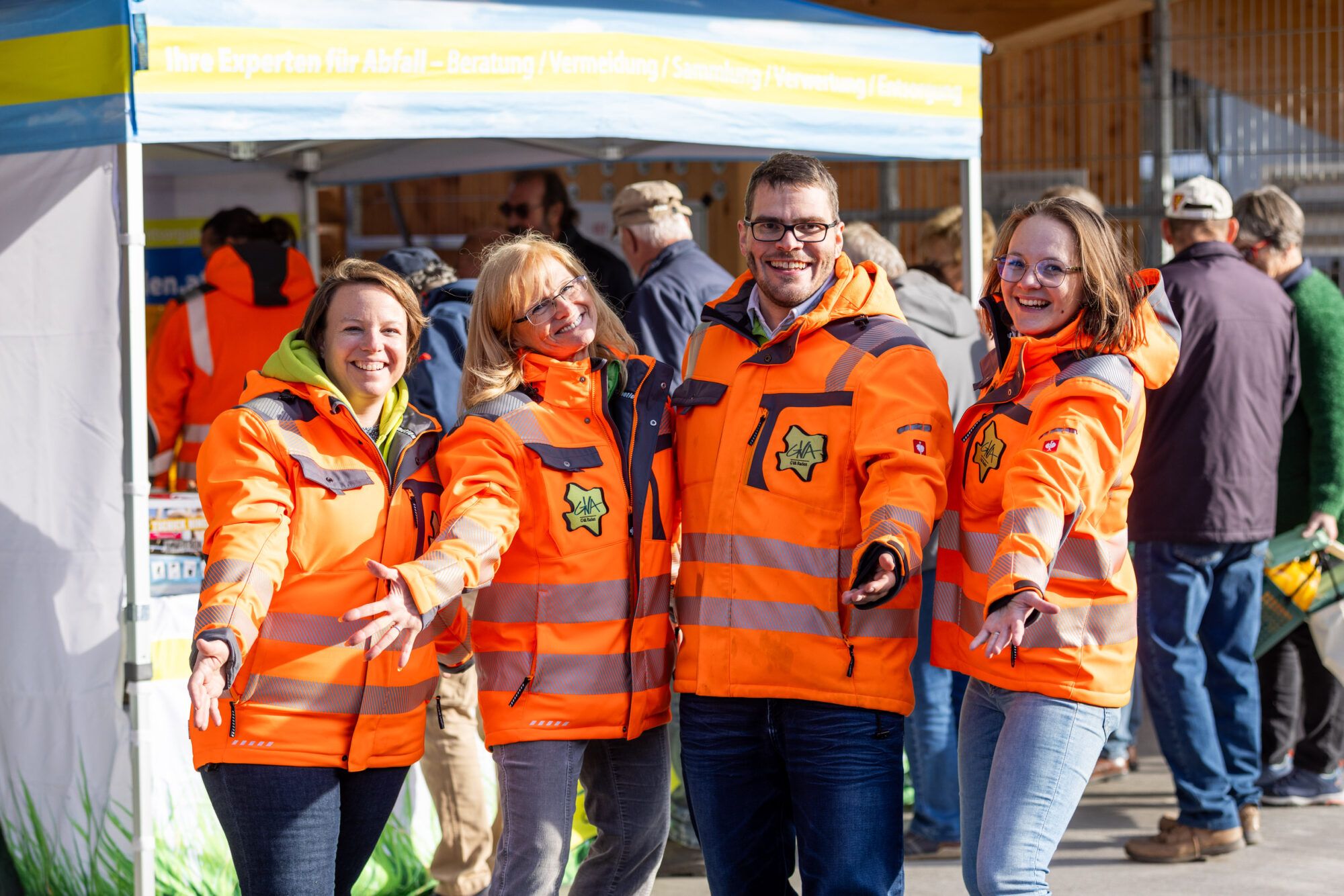 Mitarbeiter:innen der Abfallberatung, 3 Frauen, 1 Mann, alle tragen eine orange-neon Jacke