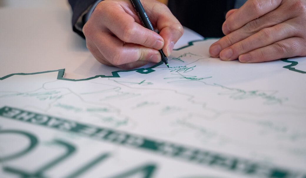 Auf dem Bild ist eine Niederösterreichkarte mit dem ReVital Logo zusehen sowie die diverse Unterschriften und eine Hand, die einen grünen Stift hält und unterschreibt.