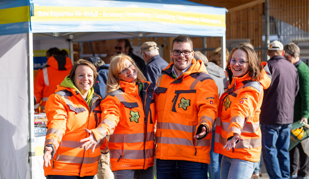 Mitarbeiter:innen der Abfallberatung, 3 Frauen, 1 Mann, alle tragen eine orange-neon Jacke