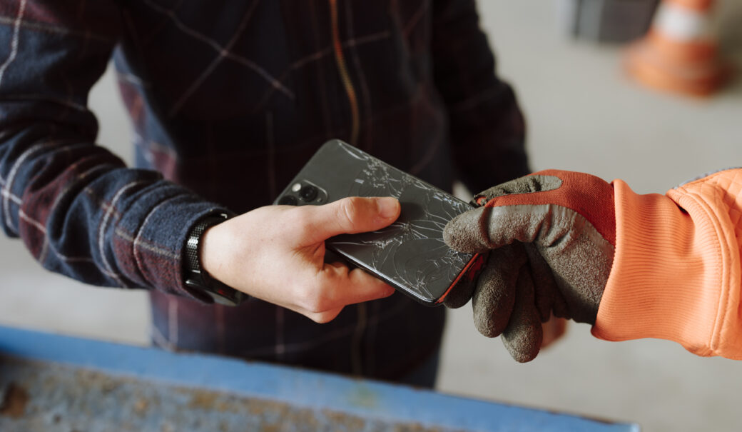 Mann im karierten Hemd gibt kaputtes Smartphone am Altstoffsammelzentrum ab.